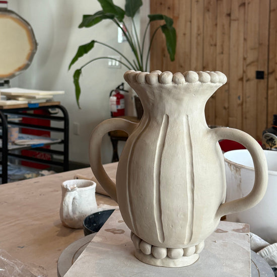 White ceramic vase with handles on a wooden surface